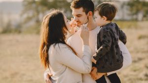 Family sharing affectionate moments outdoors with parents and child enjoying the sunny day.