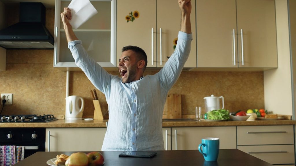 Handsome man recieve good news reading letter in the kitchen while have breakfast at home