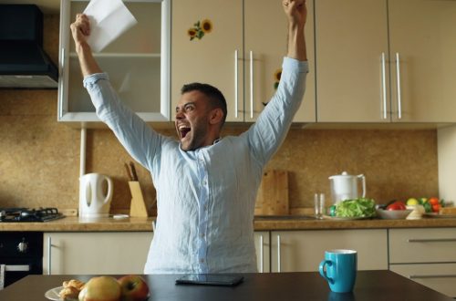 Handsome man recieve good news reading letter in the kitchen while have breakfast at home